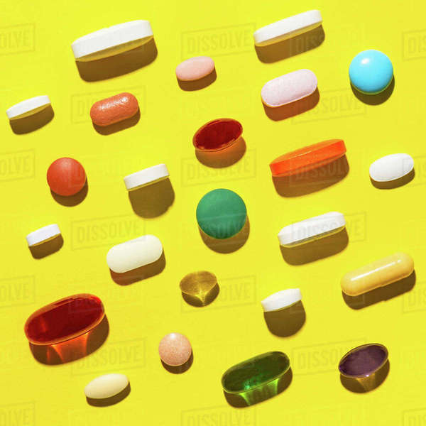 Pills and capsules on yellow Stock Photo Dissolve