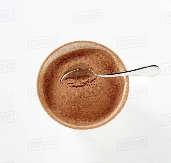 Cocoa powder in bowl with spoon Stock Photo Dissolve