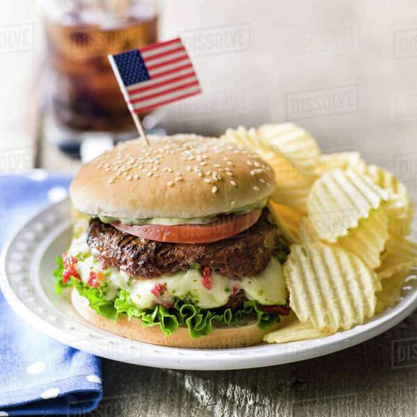 Cheeseburger and potato chips with American flag Stock Photo Dissolve
