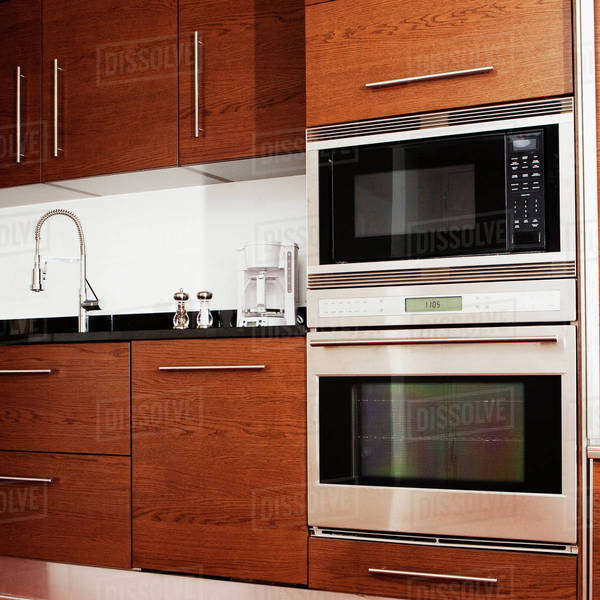 Oven, microwave, cabinets and sink in modern kitchen - Stock Photo