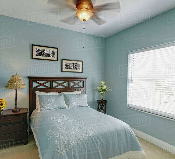 Ceiling fan over bed in bedroom Stock Photo Dissolve