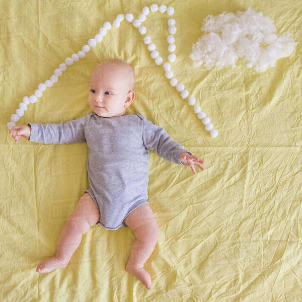 Top view of adorable infant child lying under house roof made of cotton