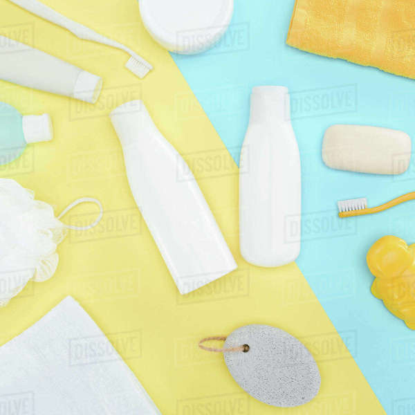 Flat lay with body lotion in bottles, toothbrushes, pumice, towel and