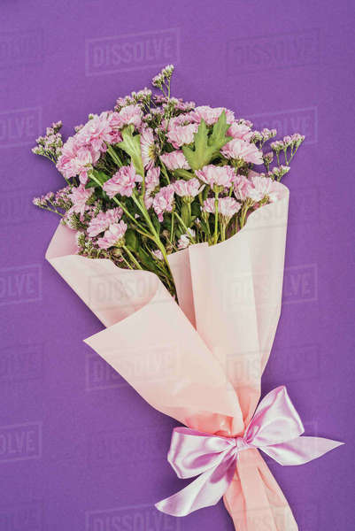 Beautiful floral bouquet with pink ribbon on violet - Stock Photo