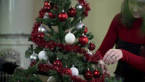 Young Romantic Couple Decorating Christmas Tree By A Fireplace