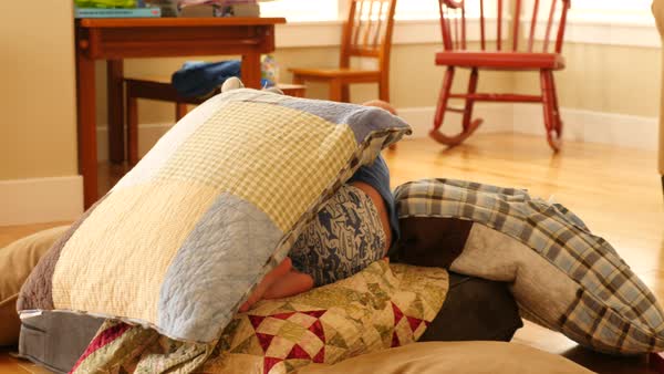 A Toddler Builds A Blanket And Pillow Fort On The Floor Of His