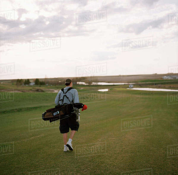 Man Carrying Golf Clubs On Course, Delisle, Saskatchewan Stock Photo