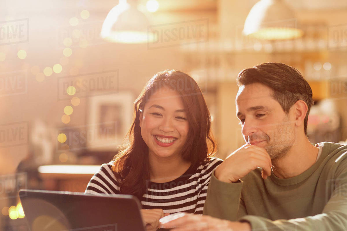 Smiling couple video chatting at laptop in cafe Royalty-free stock photo