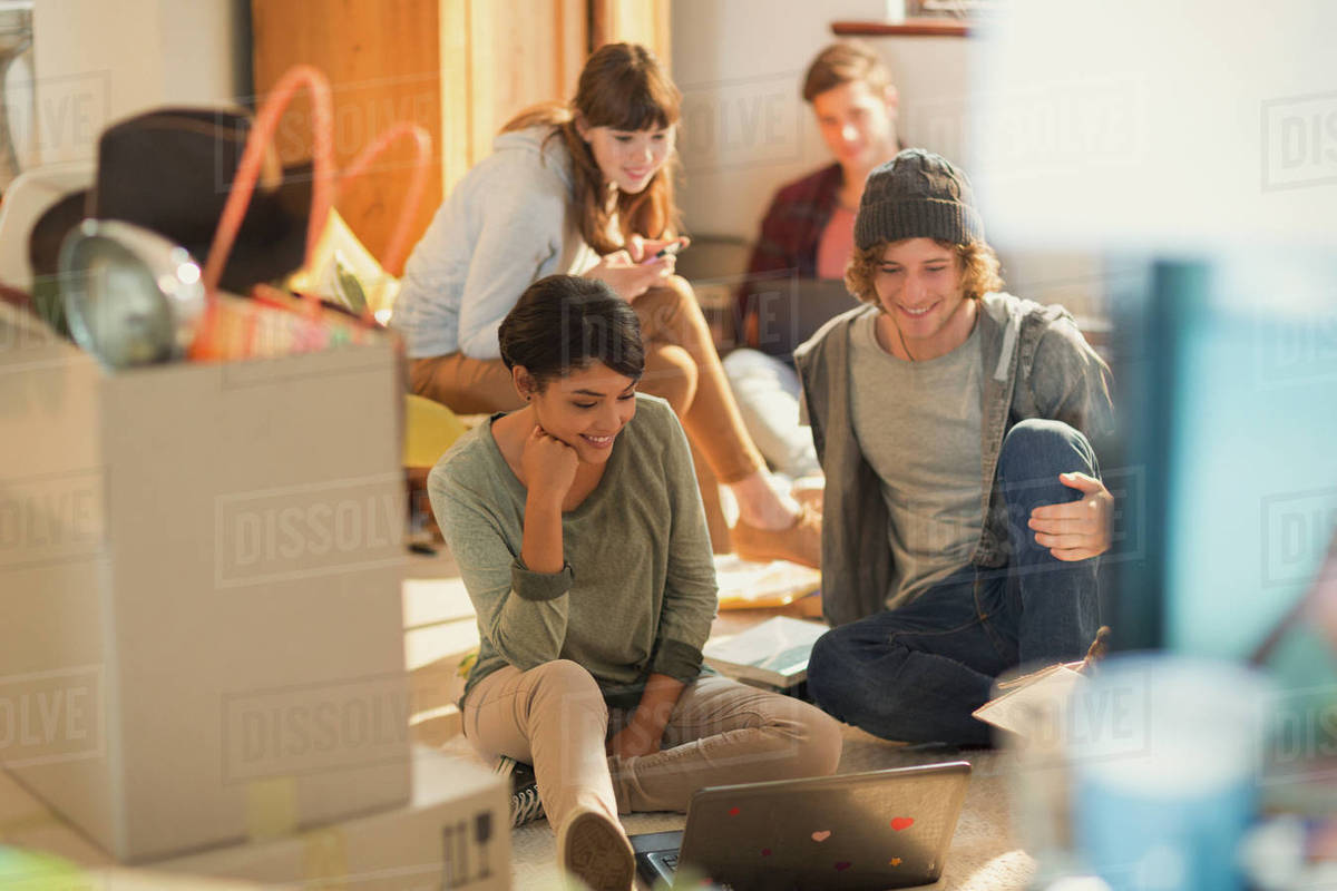 Young couples roommates using laptop unpacking moving boxes in new apartment Royalty-free stock photo