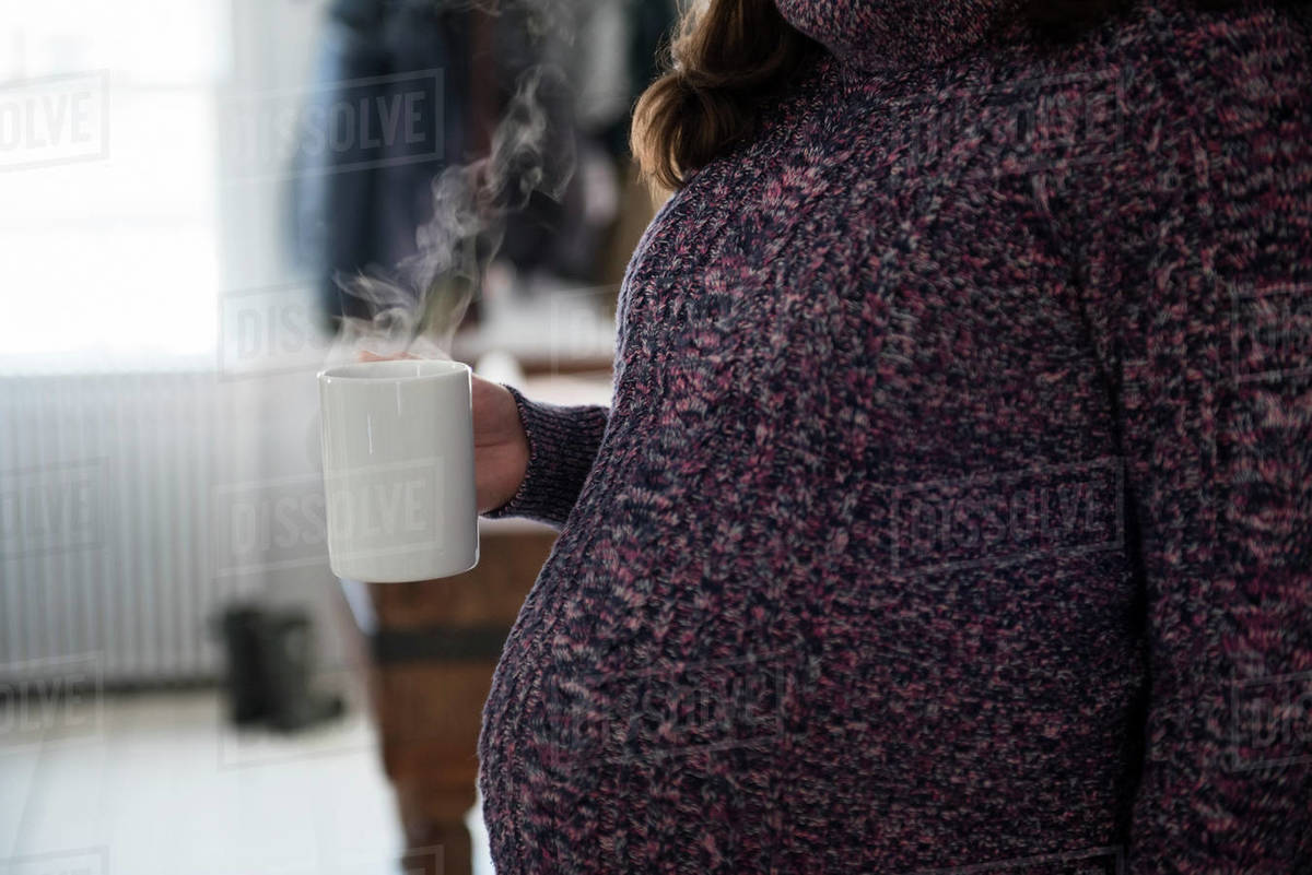 Pregnant woman holding mug with hot beverage Stock Photo Dissolve