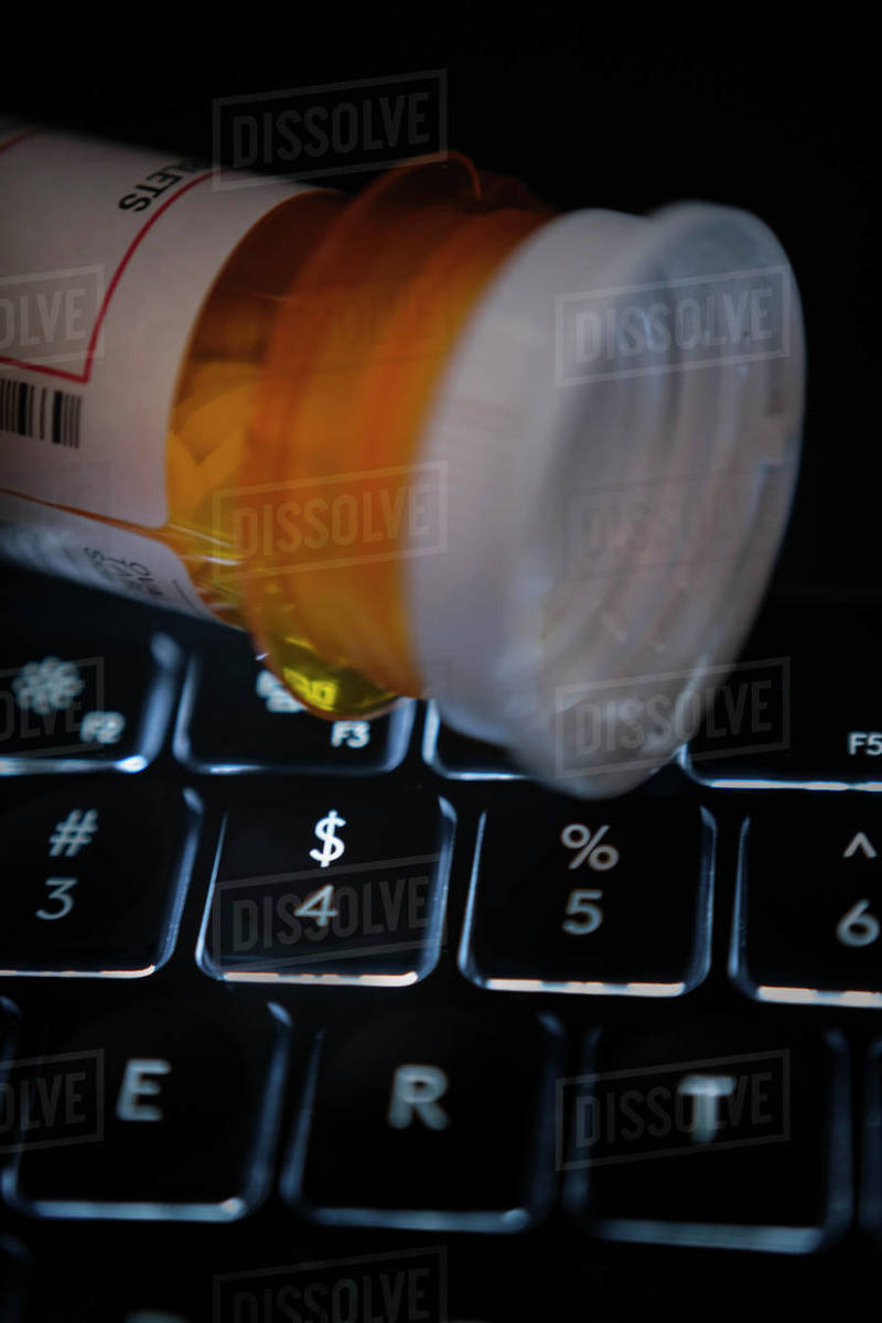 Pill bottle on computer keyboard Stock Photo Dissolve