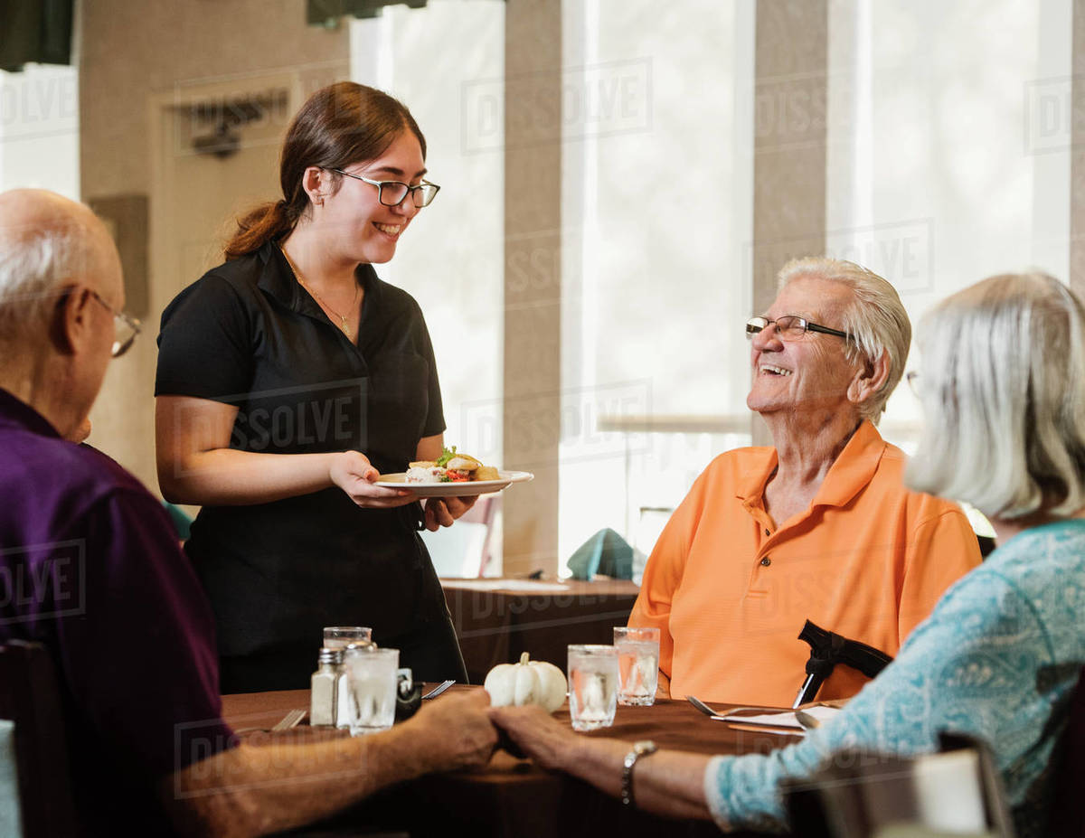 Waitress bringing meal to senior people at table Royalty-free stock photo