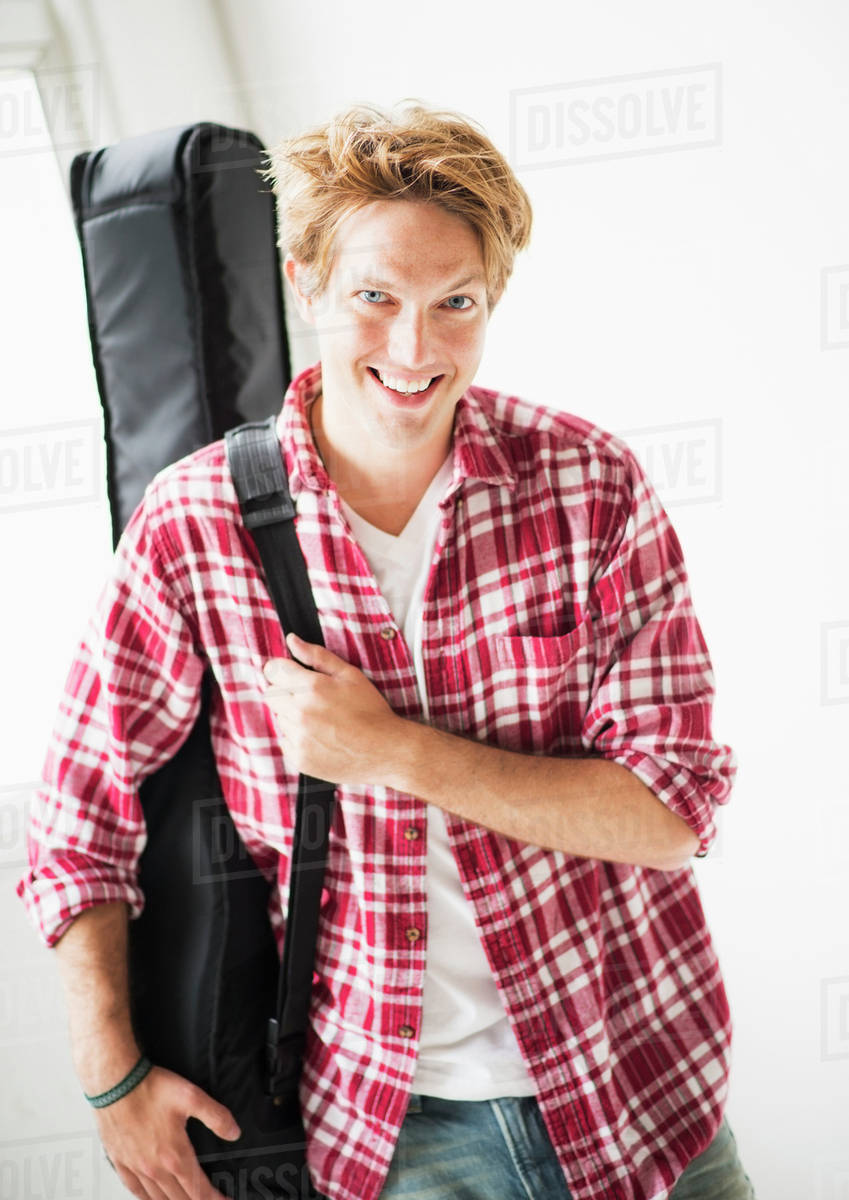 Portrait of man carrying guitar bag Stock Photo Dissolve