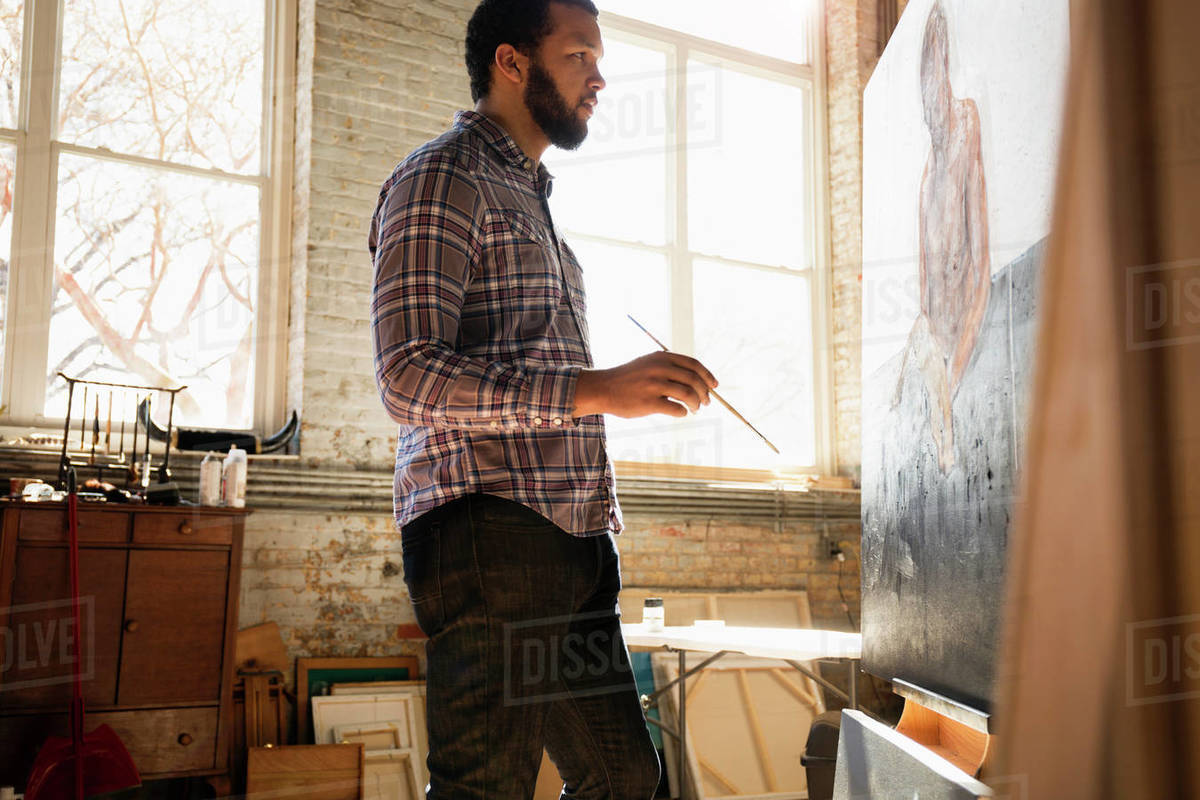 Mixed race artist painting in studio Stock Photo Dissolve