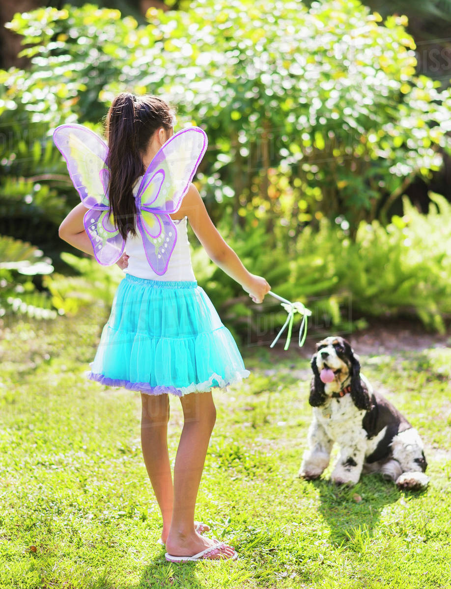 Girl (8-9) wearing fairy costume playing with dog Royalty-free stock photo