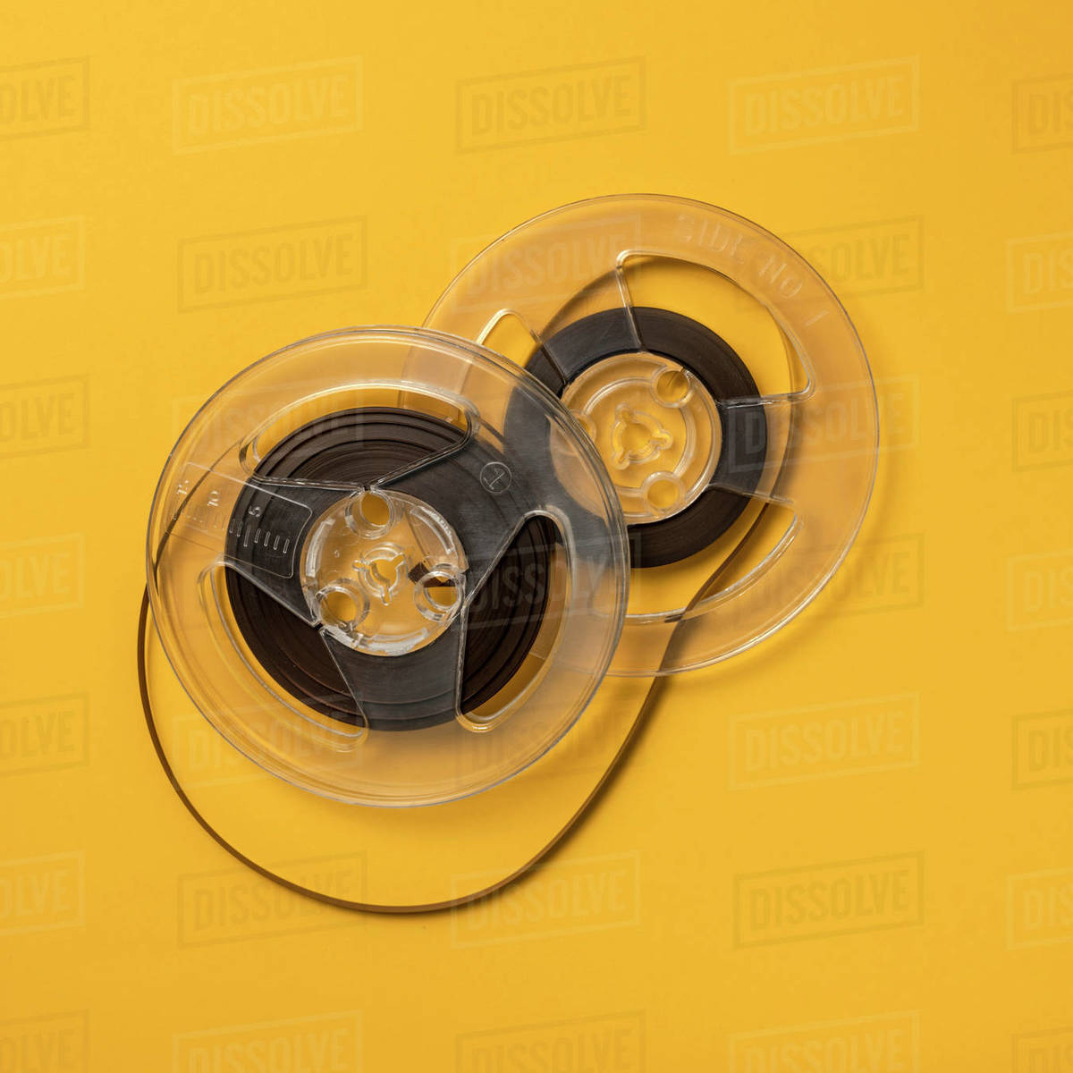 Overhead view of retro recording tape reels against yellow background Stock Photo Dissolve