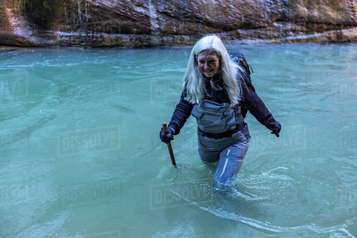 United States, Utah, Zion National Park, Senior female hiker wading The