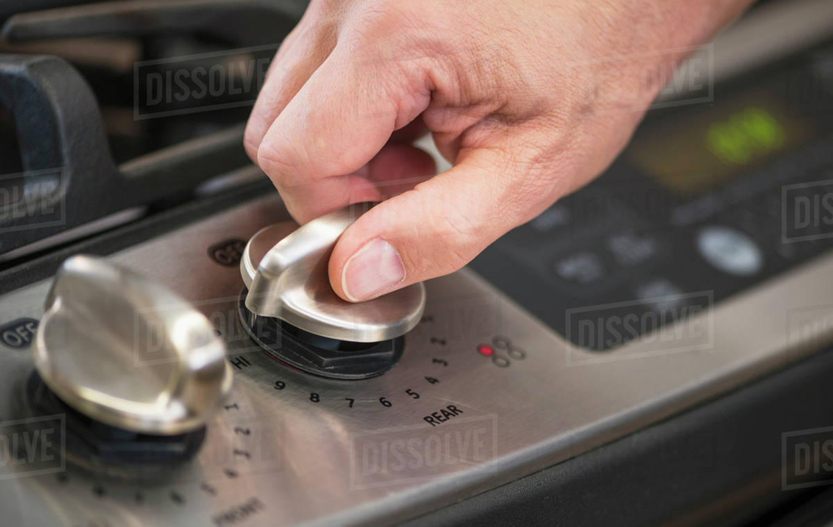 Closeup of hand adjusting stove burner Stock Photo Dissolve