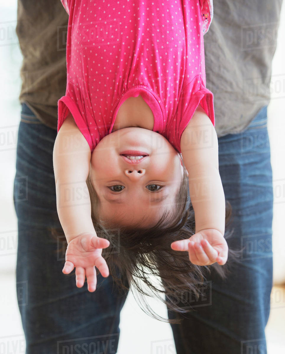 Father holding baby daughter (1217 months) upside down Stock Photo Dissolve