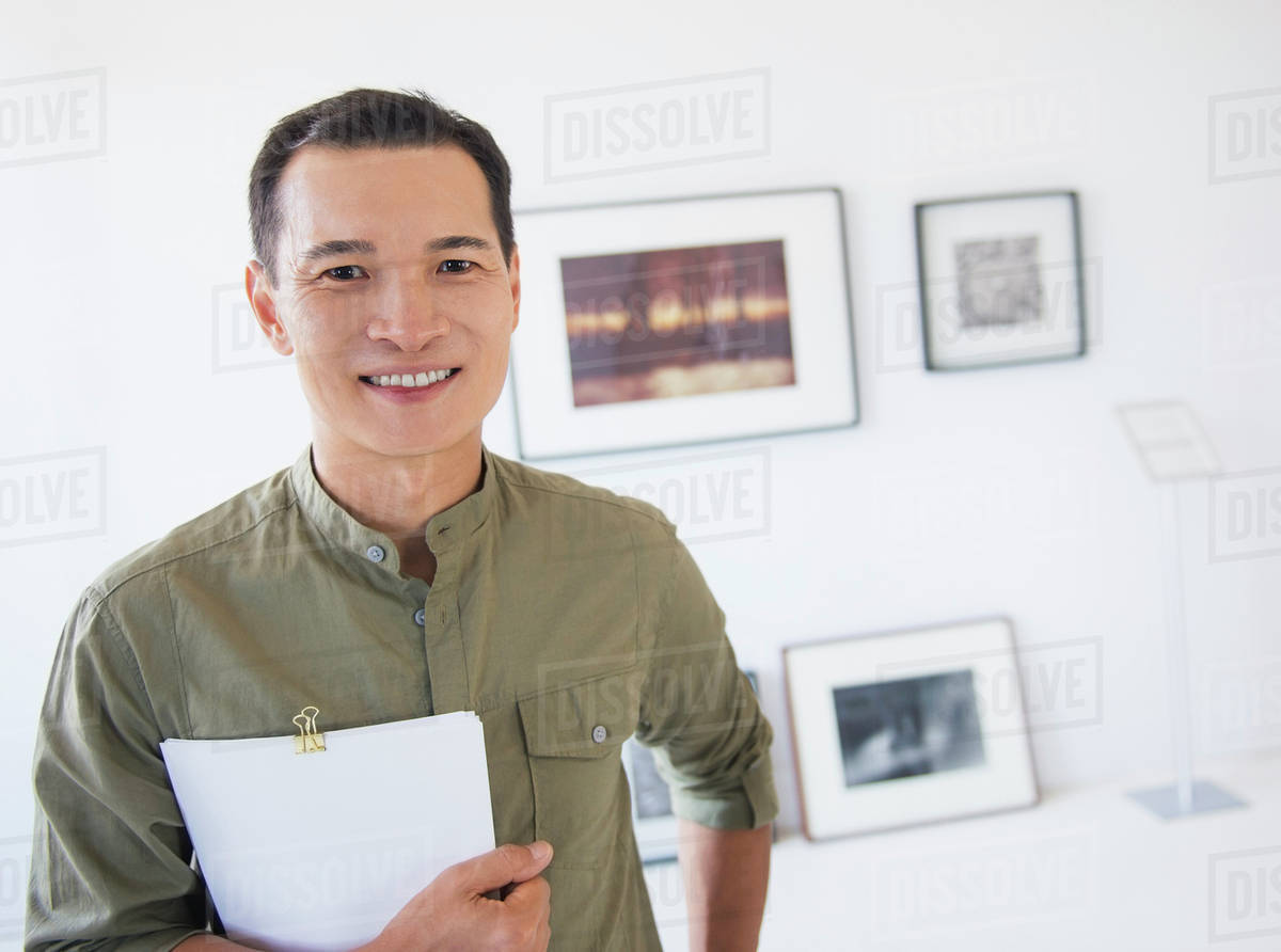 Gallery worker posing in front of newly hanged paintings Stock Photo