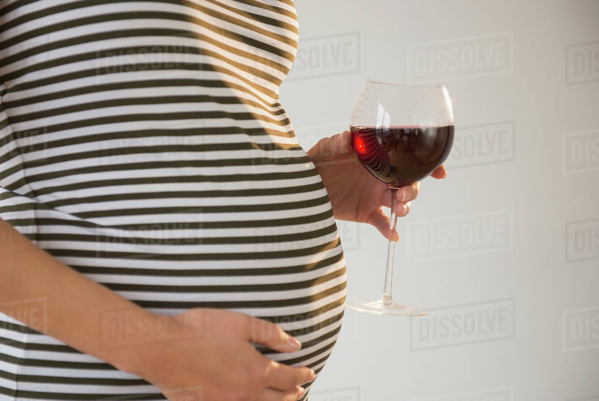 Pregnant woman holding glass of red wine Stock Photo Dissolve
