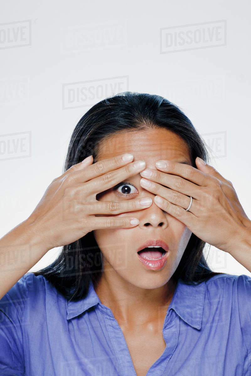 Portrait of young woman with hands covering eyes, studio shot Stock