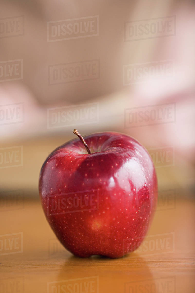 Red apple on desk Stock Photo Dissolve