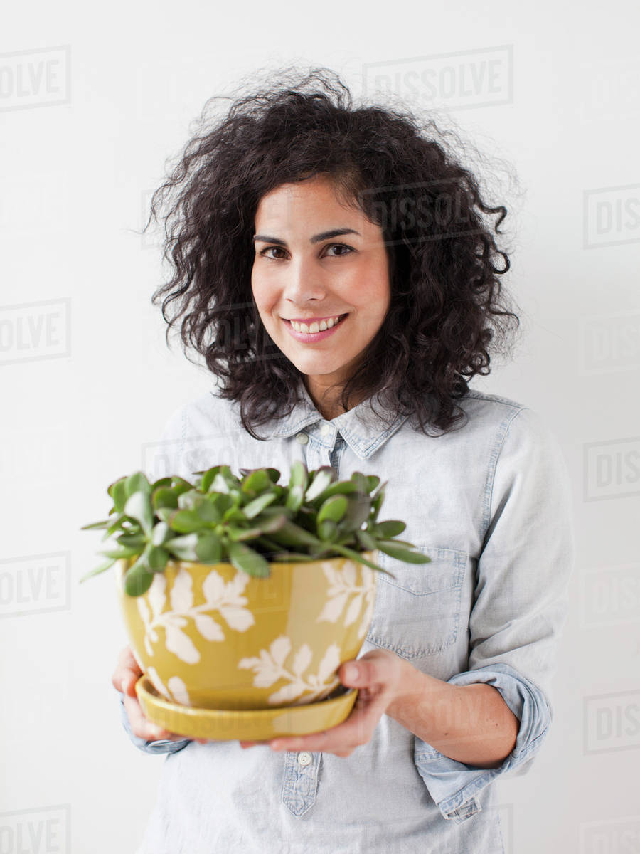Beautiful young woman holding pot plant Stock Photo Dissolve