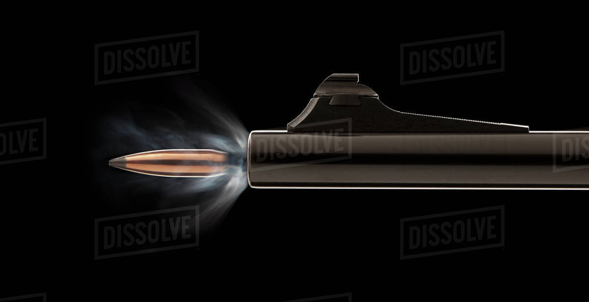 Studio shot of bullet coming out of gun barrel Stock Photo Dissolve