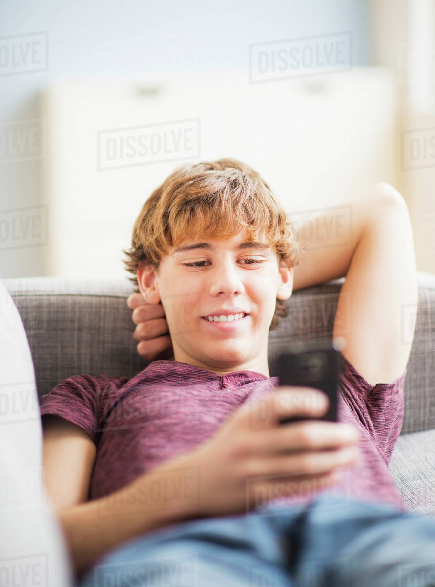 Teenage boy (1415) sitting and text messaging Stock Photo Dissolve