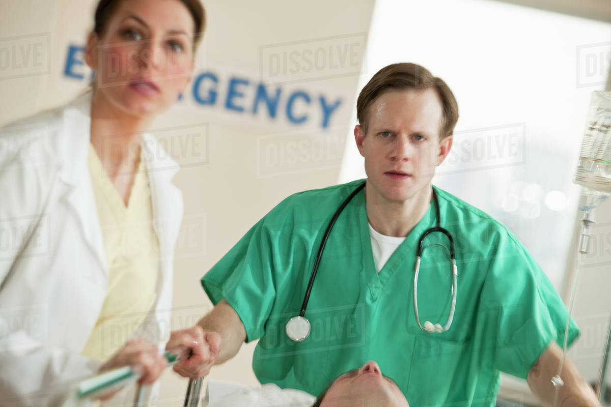 Healthcare workers pushing gurney in emergency room Stock Photo