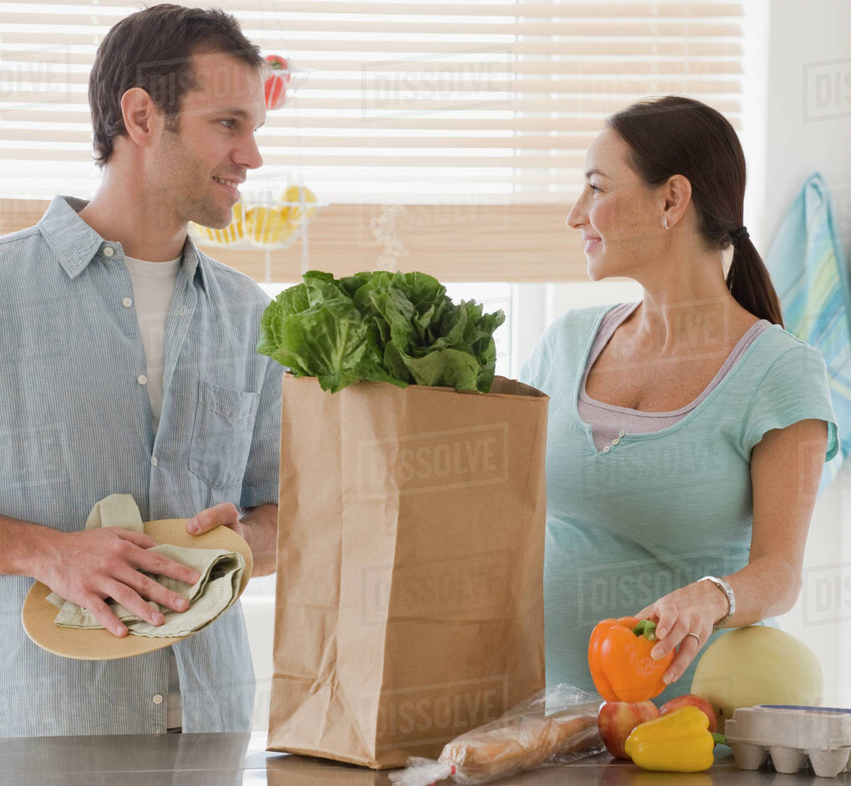 Pregnant Hispanic couple unpacking groceries Stock Photo Dissolve