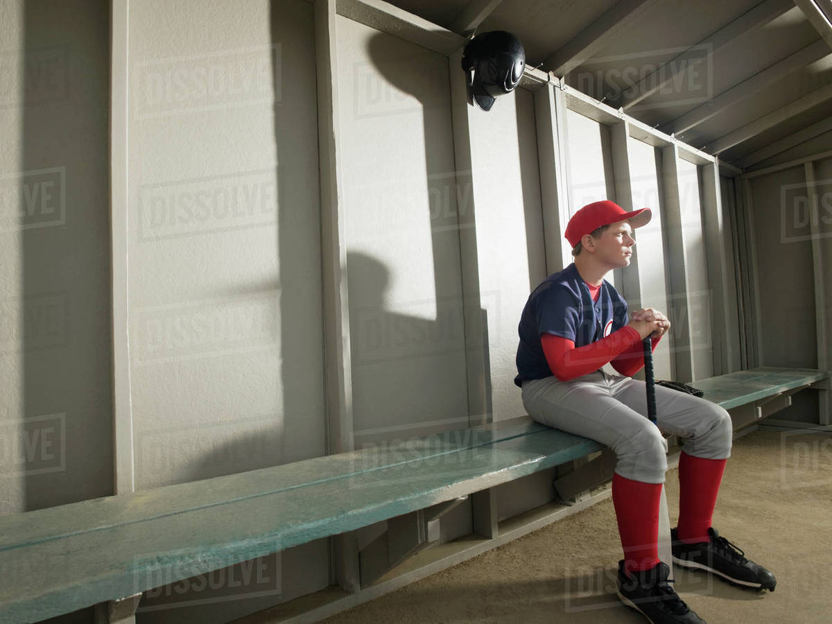 Serious baseball player sitting in dugout Stock Photo Dissolve