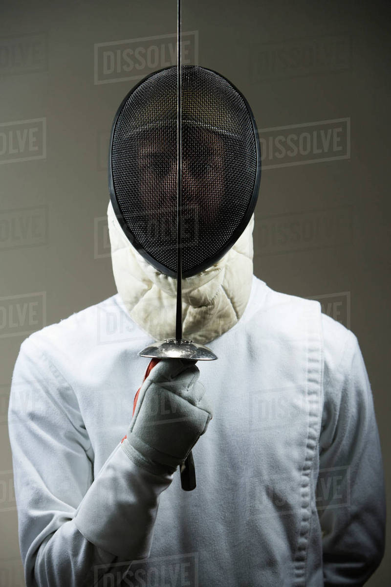 Portrait of fencer in uniform and mask holding fencing foil Stock