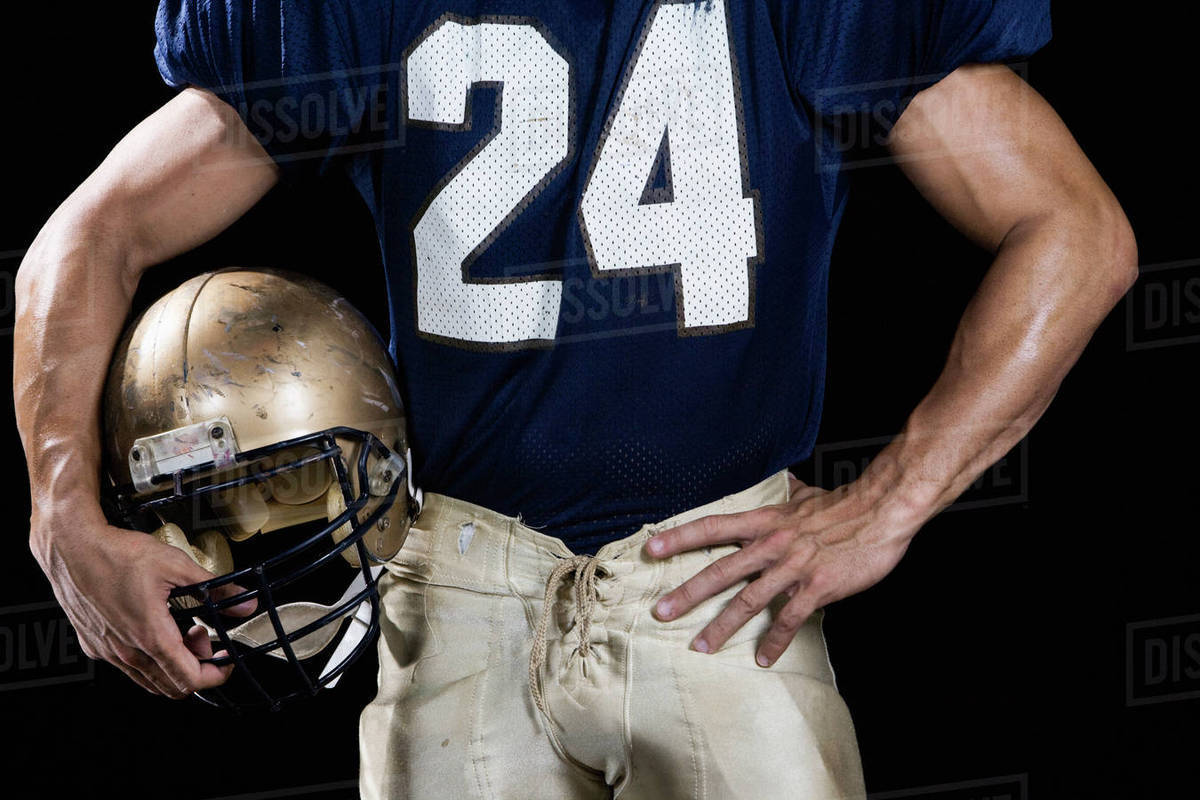 Football player wearing uniform and holding helmet Stock Photo Dissolve