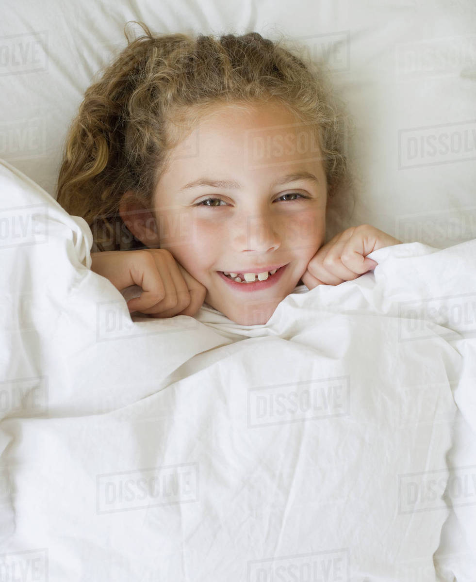 Girl pulling blanket up to chin Stock Photo Dissolve