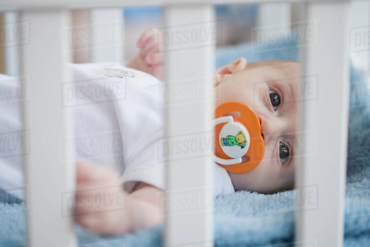 Baby in crib with pacifier Stock Photo Dissolve