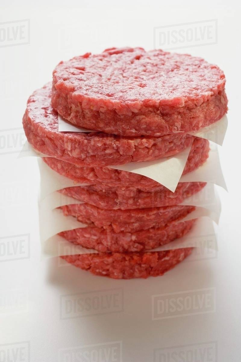 Raw burgers for hamburgers, in a pile Stock Photo Dissolve