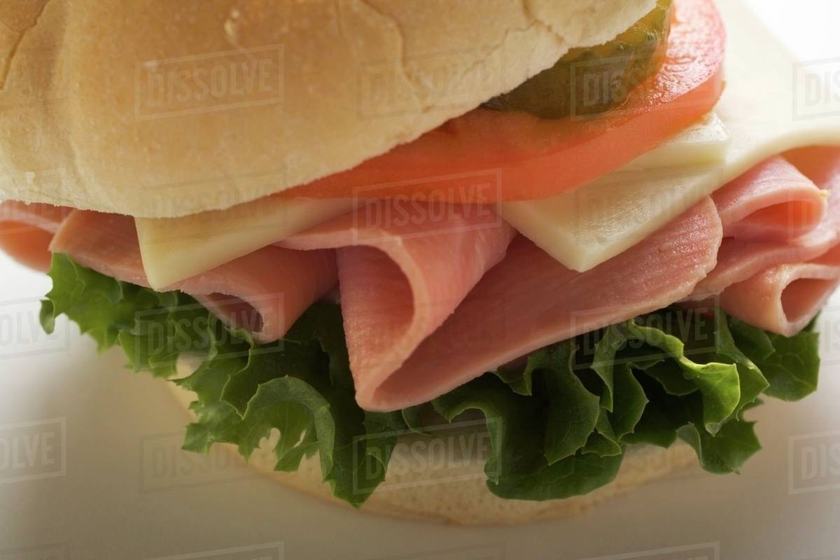 Ham, cheese, tomato and gherkin in kaiser roll Stock Photo Dissolve