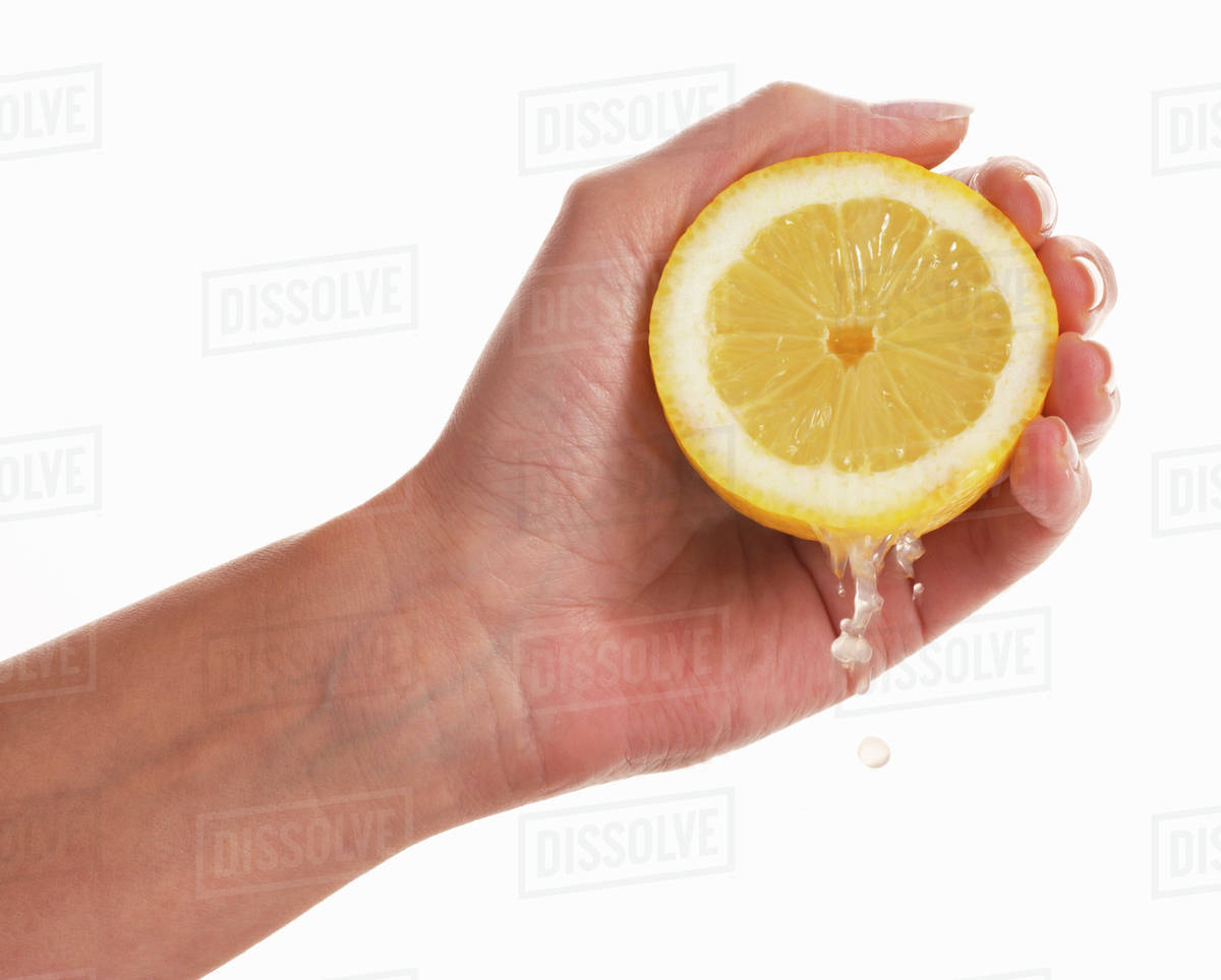 Woman's hand squeezing a lemon Stock Photo Dissolve
