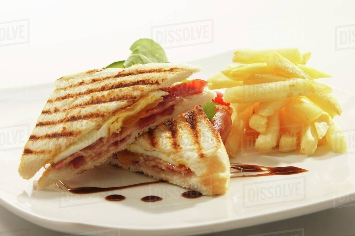 Toasted egg and bacon sandwich with chips Stock Photo Dissolve