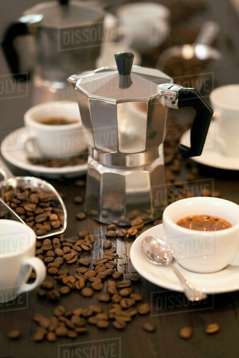 Espresso maker, cups of espresso and coffee beans Stock Photo Dissolve
