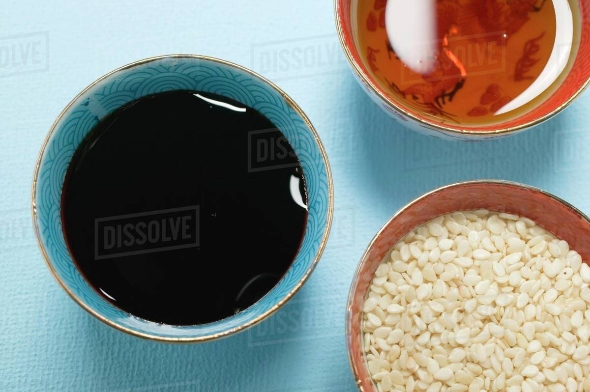 Asian sauces and sesame seeds in small bowls Stock Photo Dissolve