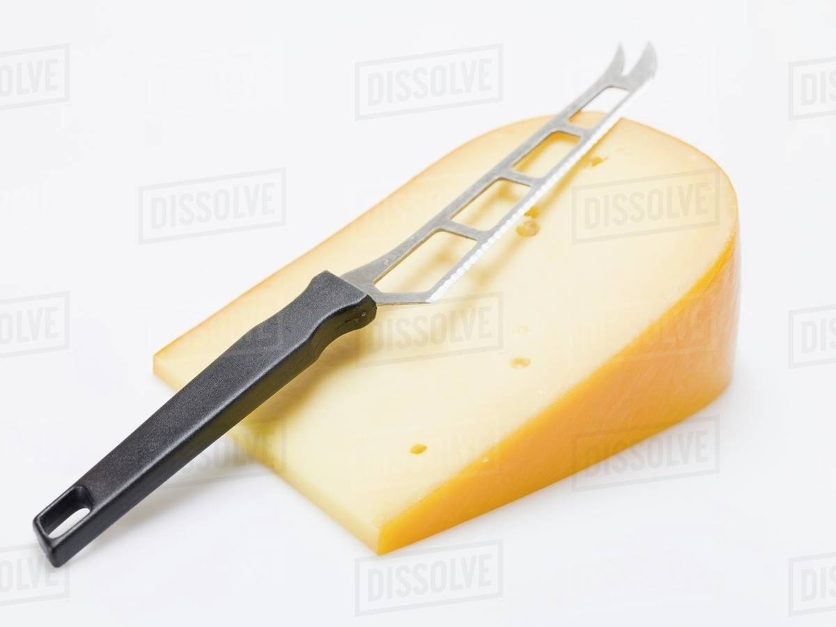 Piece of Gouda with cheese knife Stock Photo Dissolve