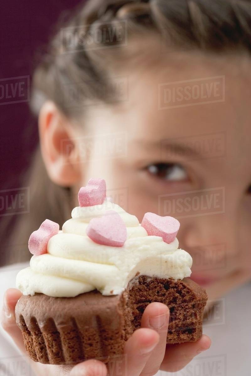 Little girl holding cupcake with sugar hearts Stock Photo Dissolve