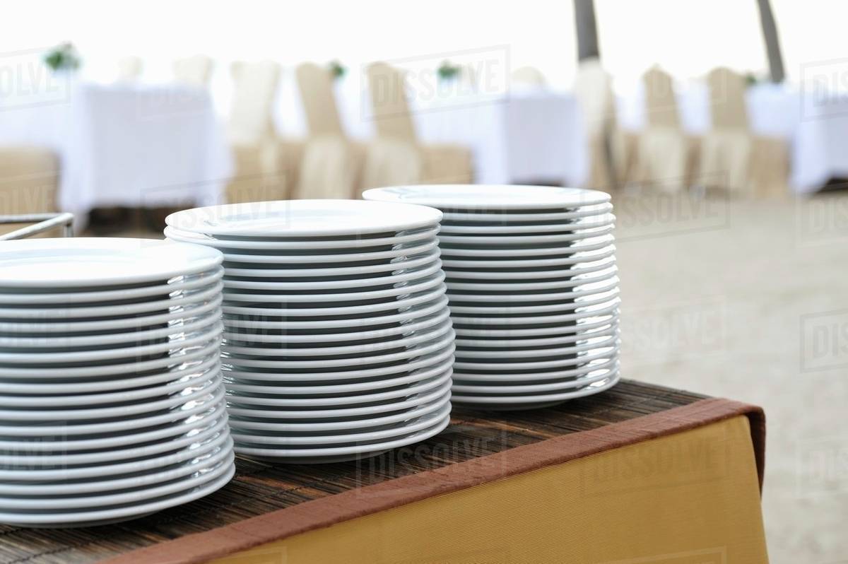 Pile of plates on a buffet table Stock Photo Dissolve