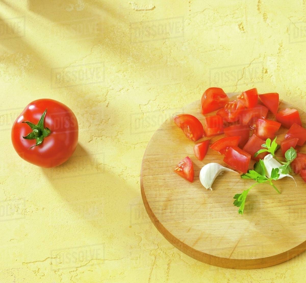 Diced tomatoes, garlic & parsley on chopping board, whole tomato