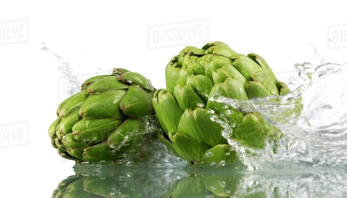 Two artichokes with splashing water Stock Photo Dissolve