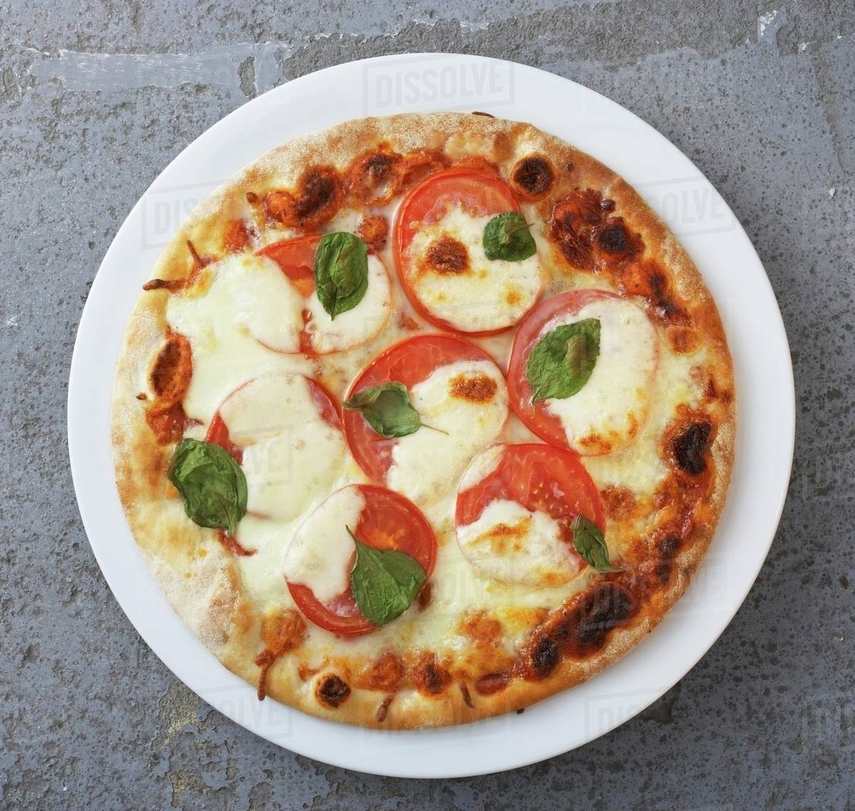 Tomato and mozzarella pizza with basil Stock Photo Dissolve