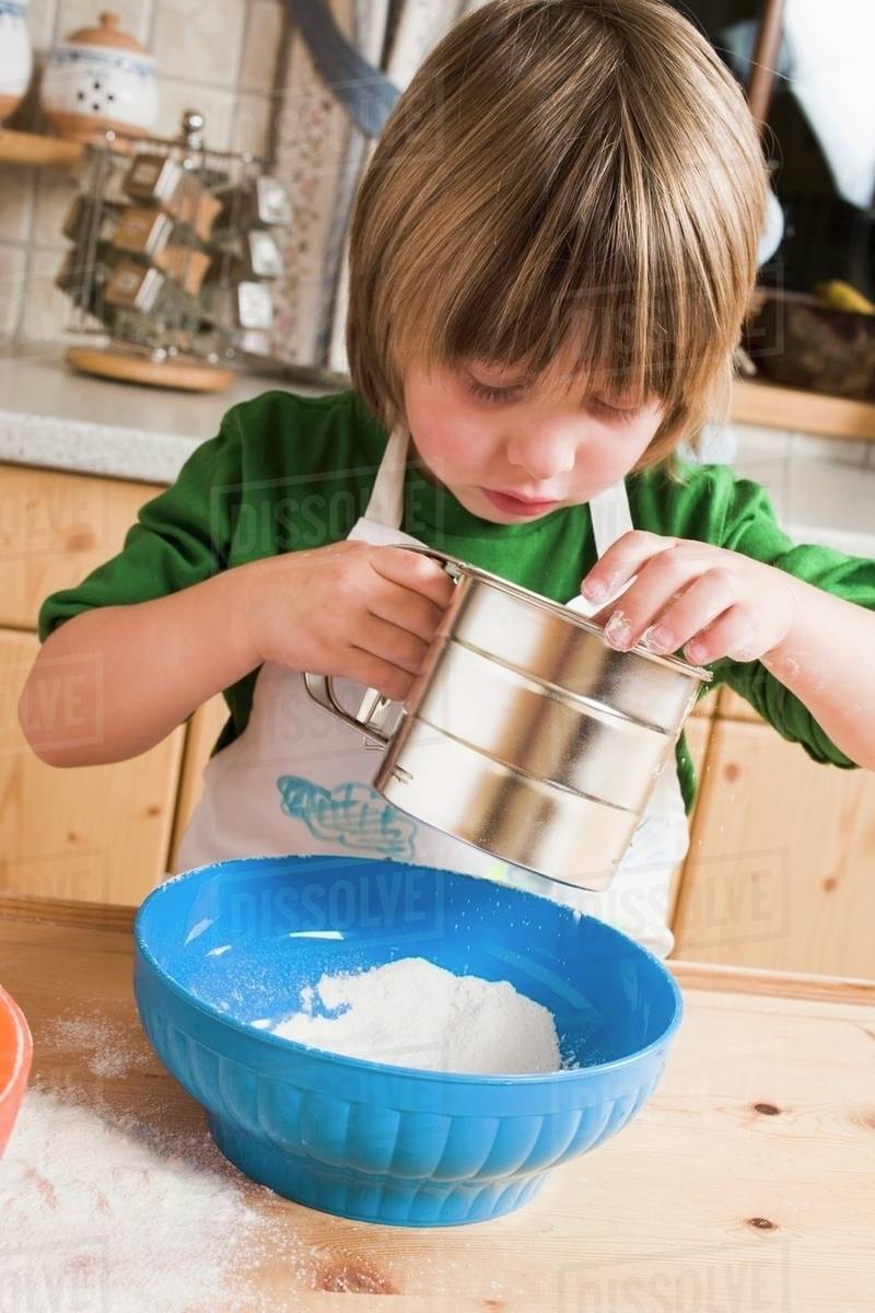 Child sieving flour into a bowl Stock Photo Dissolve